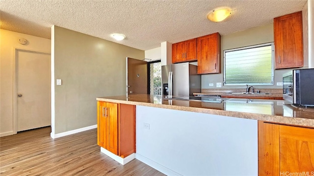 kitchen featuring appliances with stainless steel finishes, sink, a textured ceiling, and light hardwood / wood-style floors