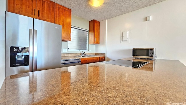 kitchen featuring stainless steel appliances, sink, and a textured ceiling