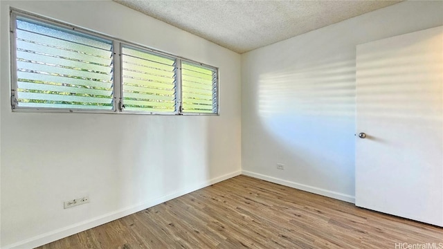 unfurnished room featuring a healthy amount of sunlight, a textured ceiling, and light wood-type flooring