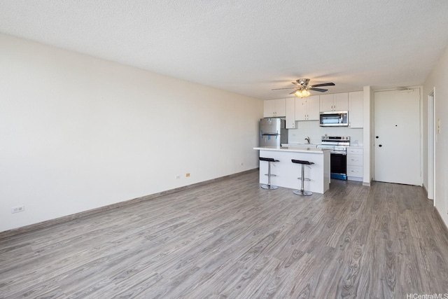 1617 Clark St Unit 702, Honolulu, HI 96822 - kitchen with stainless steel appliances, a breakfast bar, light wood-type flooring, a kitchen island, and ceiling fan