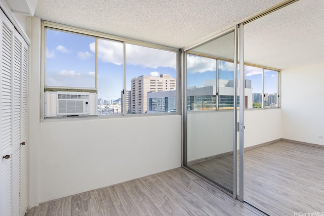 1617 Clark St Unit 702, Honolulu, HI 96822 - interior space featuring multiple windows, wood finished floors, a textured ceiling, a view of city, and cooling unit