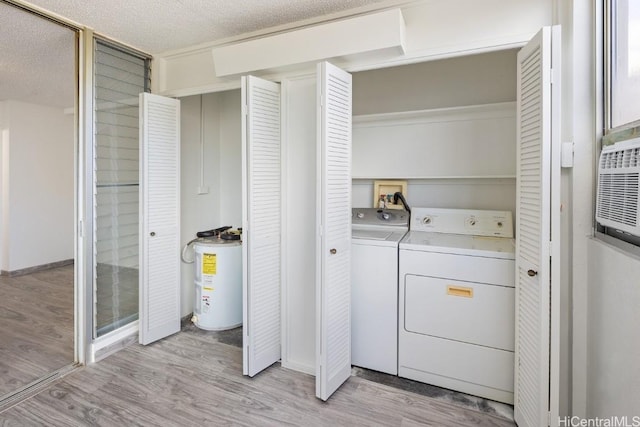 clothes washing area with separate washer and dryer, light hardwood / wood-style floors, electric water heater, and a textured ceiling