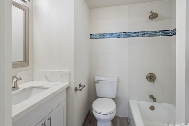 full bathroom with tiled shower / bath combo, vanity, hardwood / wood-style flooring, and toilet