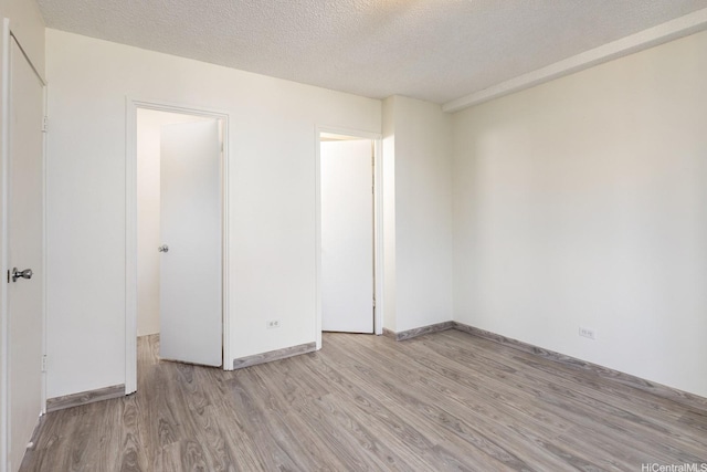 1617 Clark St Unit 702, Honolulu, HI 96822 - unfurnished bedroom featuring light wood-type flooring, a textured ceiling, and baseboards