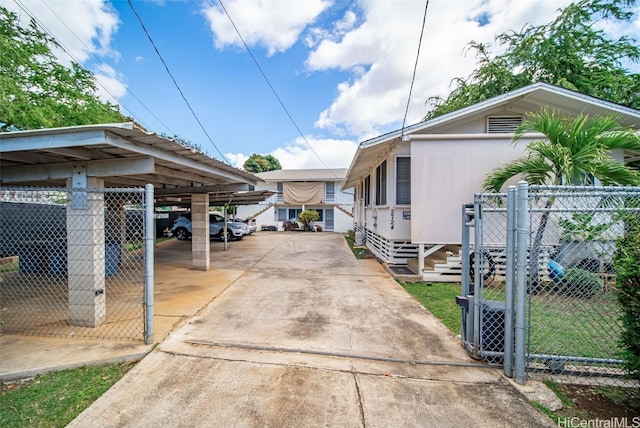 view of home's exterior featuring a carport, concrete driveway, fence, and a gate