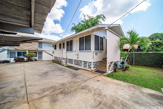 view of home's exterior with entry steps, concrete driveway, a lawn, and fence