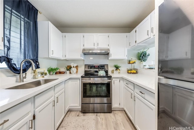 kitchen featuring sink, white cabinets, stainless steel range with electric stovetop, light hardwood / wood-style floors, and light stone countertops