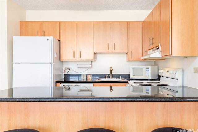 kitchen with white appliances, dark stone counters, kitchen peninsula, and sink