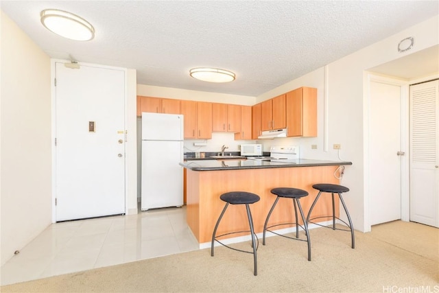 kitchen with sink, a textured ceiling, white appliances, and kitchen peninsula