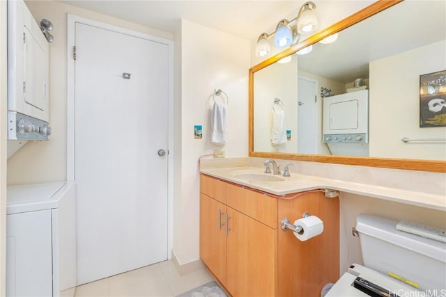 bathroom with toilet, vanity, stacked washing maching and dryer, and tile patterned flooring