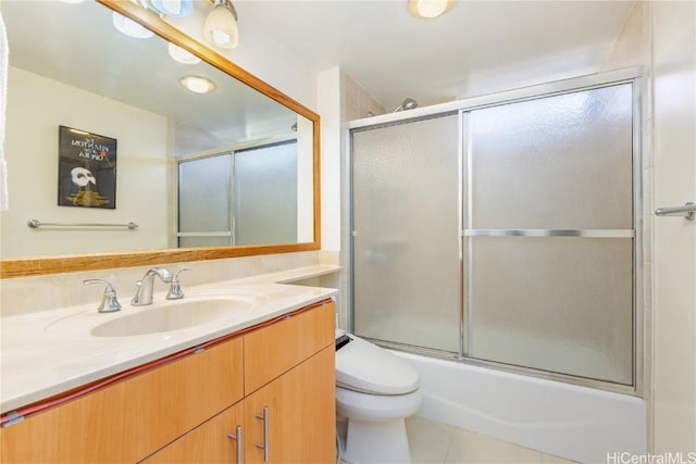 full bathroom with vanity, tile patterned floors, combined bath / shower with glass door, and toilet