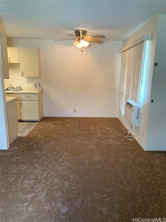 unfurnished living room with ceiling fan, light carpet, cooling unit, a textured ceiling, and a sink