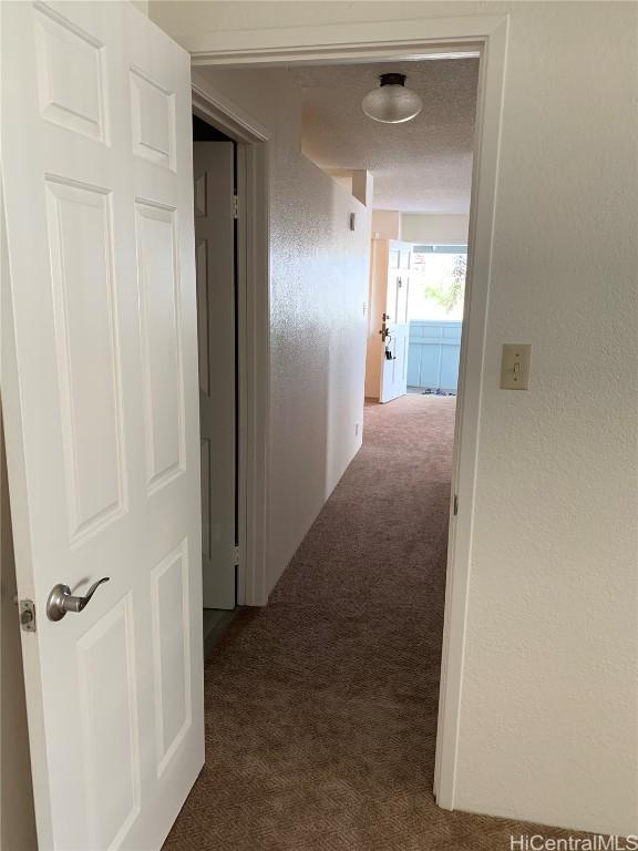 hall with carpet floors and a textured wall