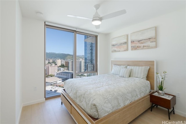 bedroom featuring access to exterior, floor to ceiling windows, ceiling fan, and light wood-type flooring