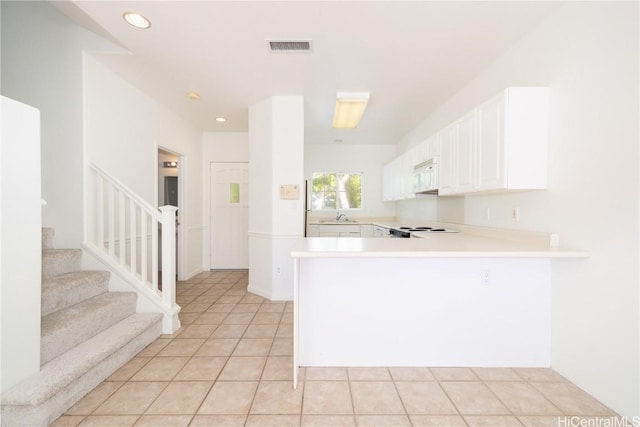 kitchen featuring light tile patterned flooring, kitchen peninsula, sink, and white cabinets