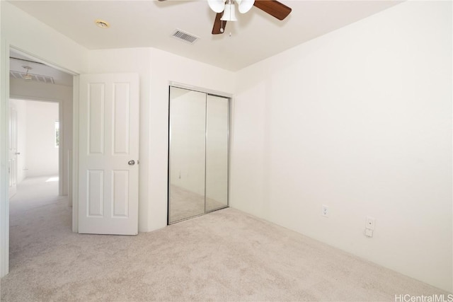 unfurnished bedroom featuring ceiling fan, a closet, and light carpet