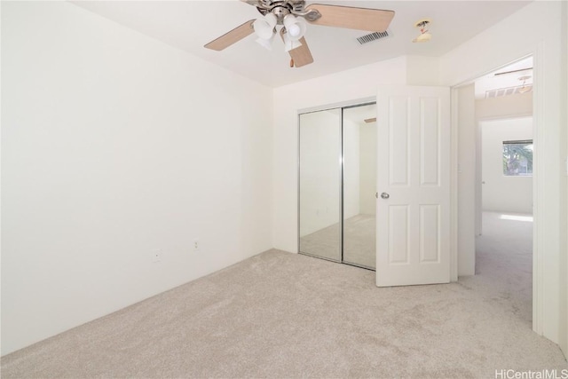 unfurnished bedroom with light carpet, ceiling fan, and a closet