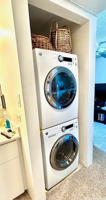 laundry area featuring stacked washer / dryer and light colored carpet