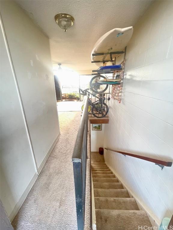 staircase with carpet and a textured ceiling