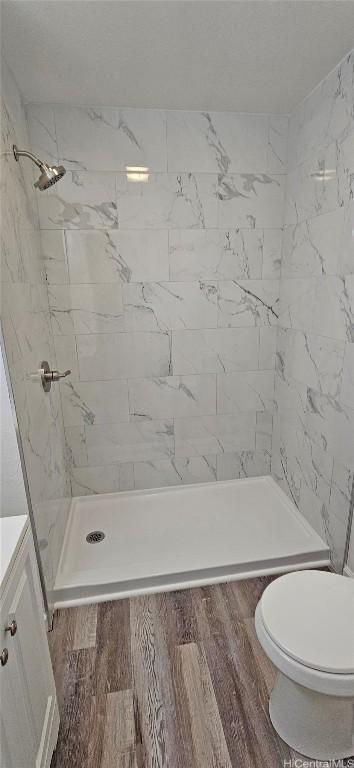 bathroom with vanity, wood-type flooring, toilet, and tiled shower