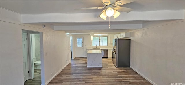 kitchen with beamed ceiling, white cabinetry, sink, hardwood / wood-style flooring, and stainless steel appliances