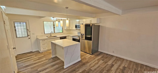 kitchen with a kitchen island, appliances with stainless steel finishes, pendant lighting, white cabinets, and light hardwood / wood-style floors