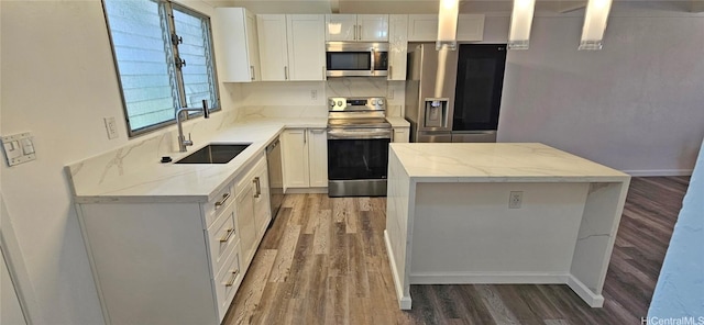 kitchen featuring stainless steel appliances, white cabinetry, light stone countertops, and sink