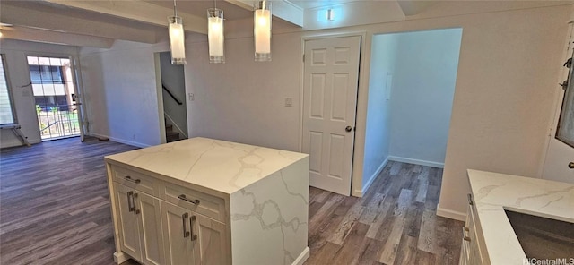 kitchen with hanging light fixtures, dark hardwood / wood-style flooring, a kitchen island, and light stone counters