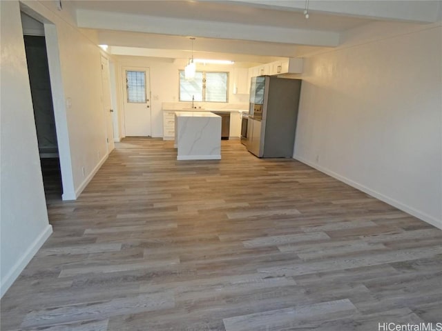 kitchen with sink, light hardwood / wood-style flooring, appliances with stainless steel finishes, hanging light fixtures, and white cabinets