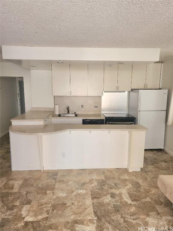 kitchen with sink, white refrigerator, kitchen peninsula, stove, and backsplash