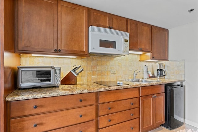 kitchen featuring black electric stovetop, light stone countertops, sink, and decorative backsplash