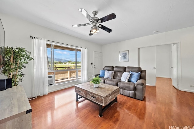 living area featuring wood finished floors, a ceiling fan, and baseboards