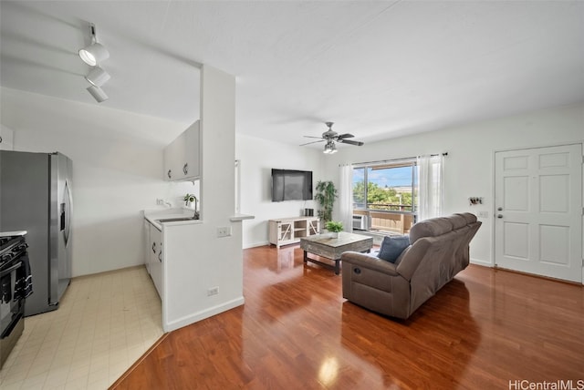 living room featuring light wood-style floors, track lighting, baseboards, and a ceiling fan