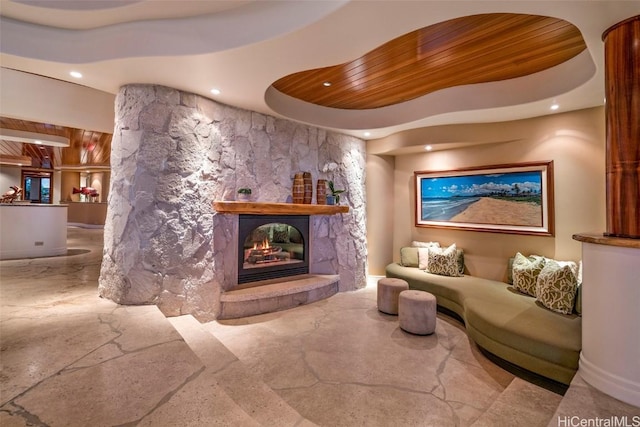 interior space featuring a tray ceiling, a stone fireplace, and wooden ceiling