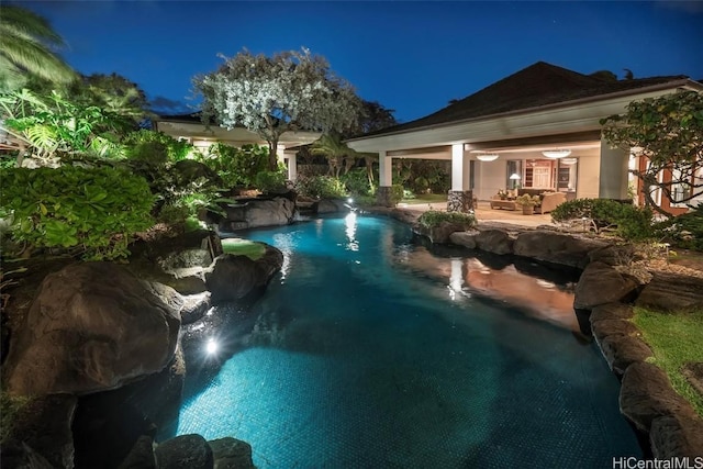 pool at night with a patio and pool water feature