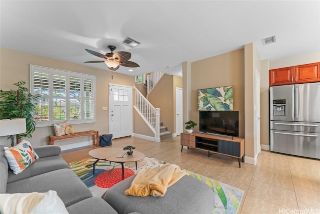 living room with stairs, baseboards, visible vents, and a ceiling fan