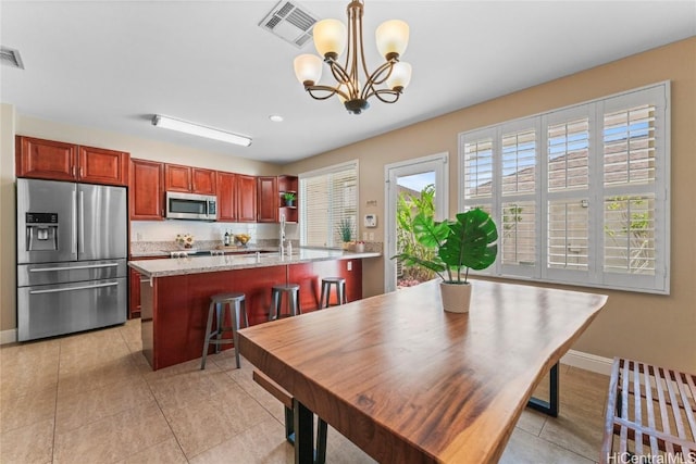 dining area featuring light tile patterned floors, visible vents, a notable chandelier, and baseboards