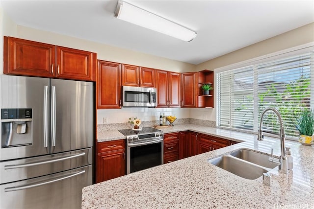 kitchen with light stone counters, appliances with stainless steel finishes, and a sink