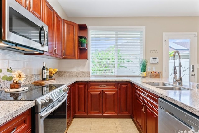 kitchen with light stone counters, light tile patterned floors, a sink, decorative backsplash, and stainless steel appliances