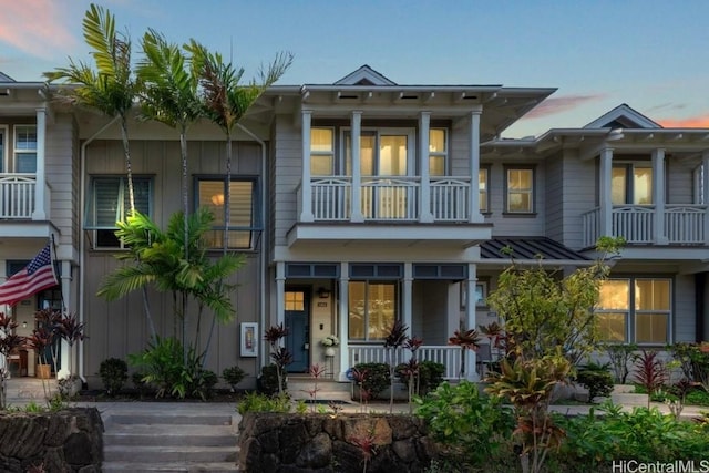 view of front of house featuring a balcony, a standing seam roof, covered porch, board and batten siding, and metal roof