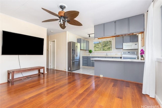 kitchen featuring stainless steel refrigerator with ice dispenser, stove, light hardwood / wood-style flooring, and kitchen peninsula