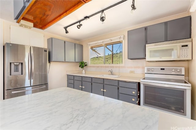 kitchen featuring tasteful backsplash, sink, gray cabinetry, and white appliances