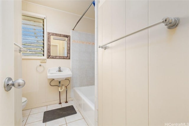 bathroom with tile patterned flooring, tiled shower / bath, and toilet