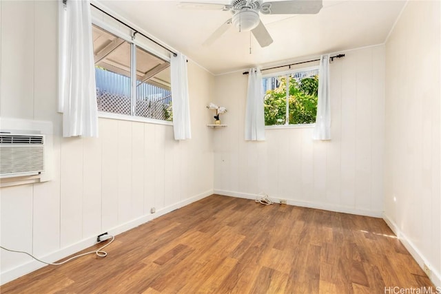 spare room featuring hardwood / wood-style floors, a wall mounted air conditioner, and ceiling fan