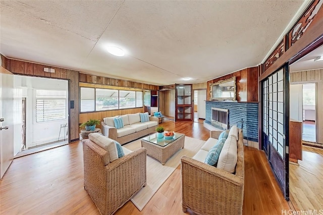 living area with plenty of natural light, wood walls, a brick fireplace, and light wood-style flooring