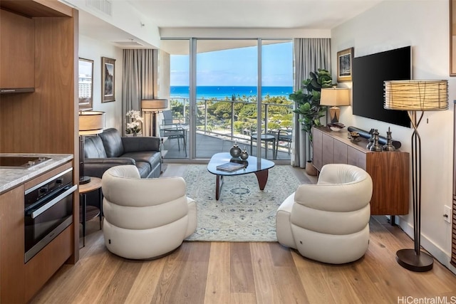 living area featuring light wood-type flooring, visible vents, and floor to ceiling windows