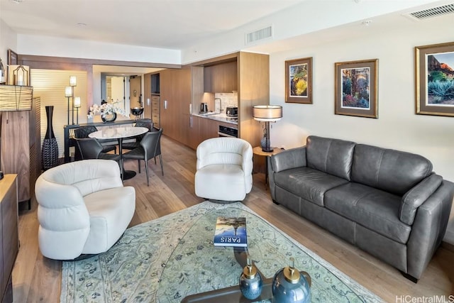 living area with light wood-style flooring and visible vents