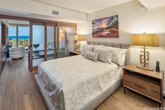 bedroom with access to exterior, wood-type flooring, and visible vents