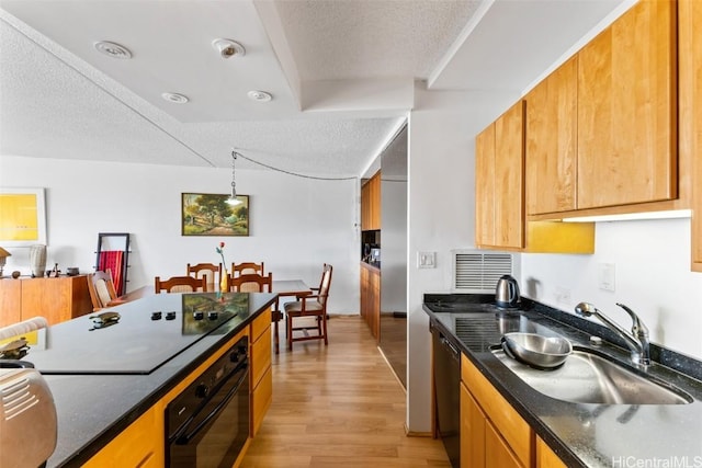 kitchen featuring sink, a textured ceiling, dark stone countertops, light hardwood / wood-style flooring, and black appliances