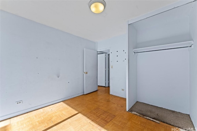 unfurnished bedroom featuring parquet flooring and a closet